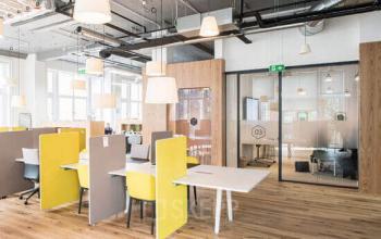 Modern office space rental at Bleicherweg 10 in Zürich Enge with vibrant yellow dividers, sleek furniture, and an open floor plan.
